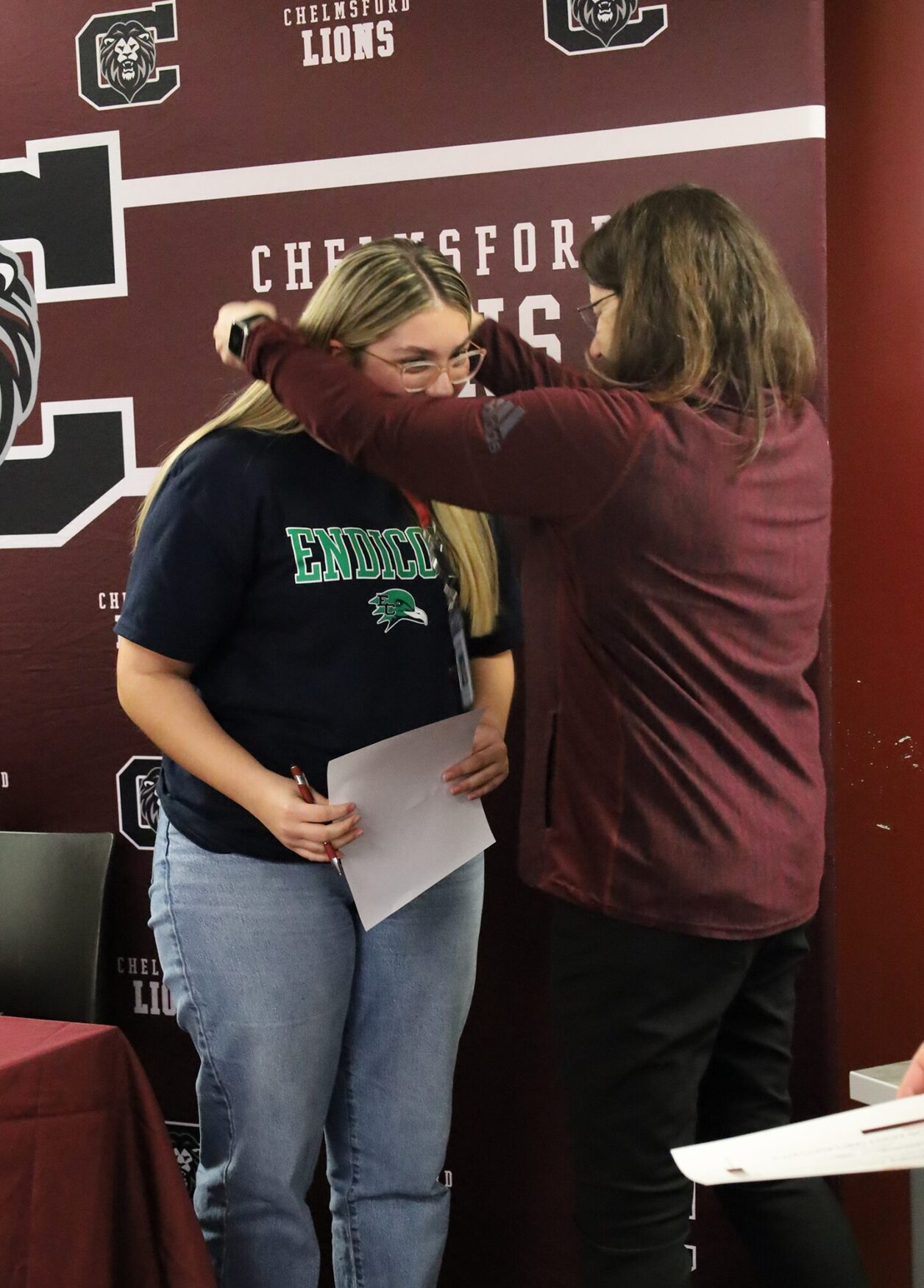 Senior Mia Troncoso is presented an honorary teachers badge and lanyard from Chelmsford Public Schools Assistant Superintendent Linda Hirsch during the Future Teachers Signing Day ceremony on May 22, 2026.