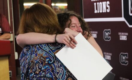 School Committee vice chair Susan Mackinnon receives a hug from her former student Elizabeth Dunlea, a senior who is planning to study secondary education at Bridgewater State University.